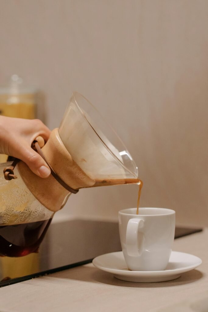 Close-up of handcrafted coffee being poured into a white ceramic cup indoors.