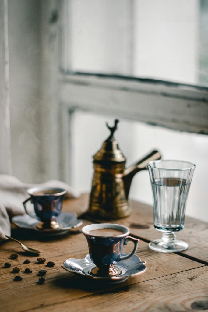 An elegant setup of Turkish coffee with porcelain cups by a window.