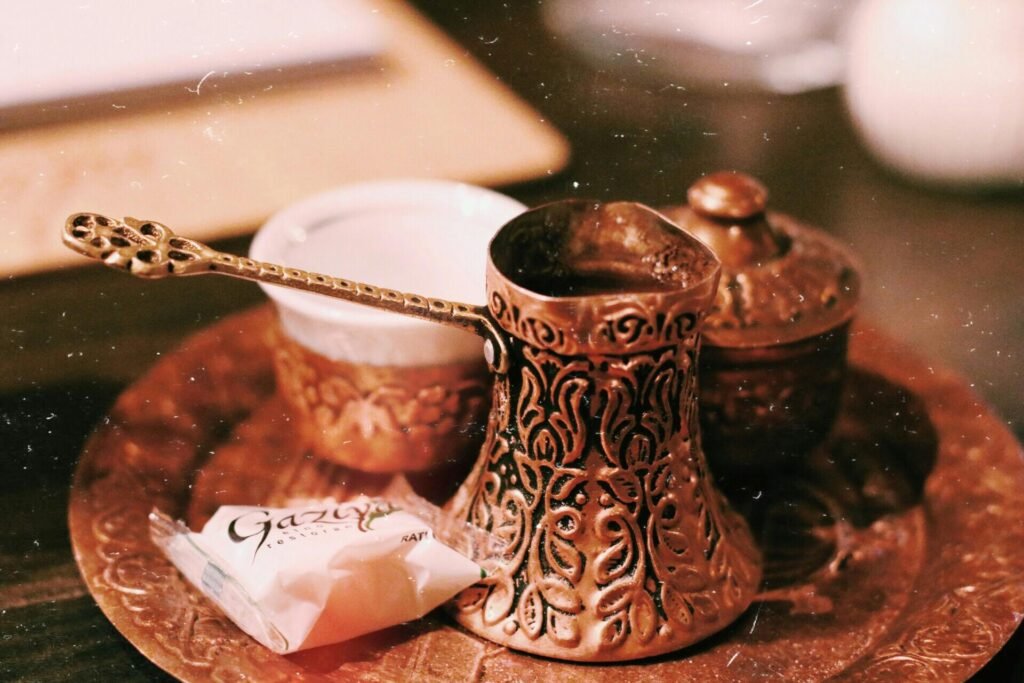 Close-up of a traditional Turkish coffee set featuring a copper pot and a sweet treat.