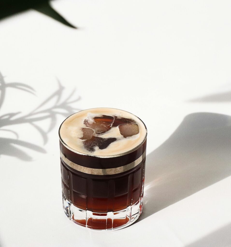 A close-up of cold brew coffee in a glass on a bright, sunny day with artistic shadows.