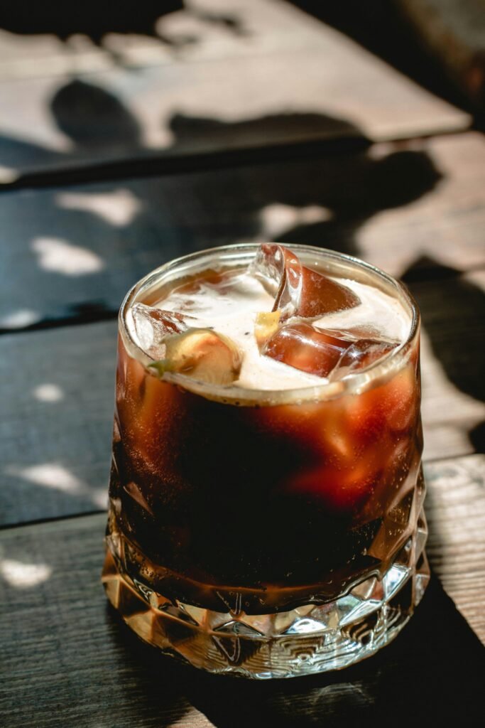 Close-up of a refreshing iced cold brew coffee in a glass with sunlight and shadows.