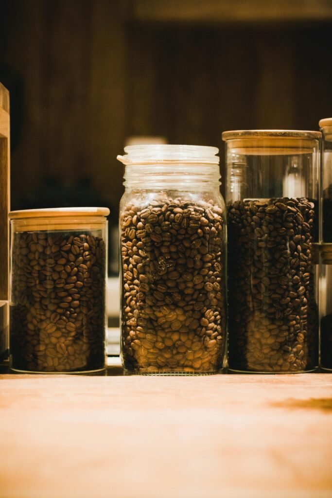 A warm-toned close-up of coffee beans stored in glass jars, evoking a cozy atmosphere.