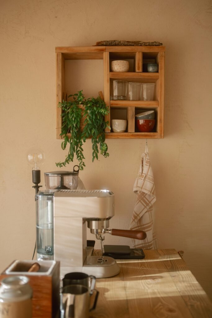 Elegant coffee setup in a minimalist home kitchen with wooden shelves and greenery.