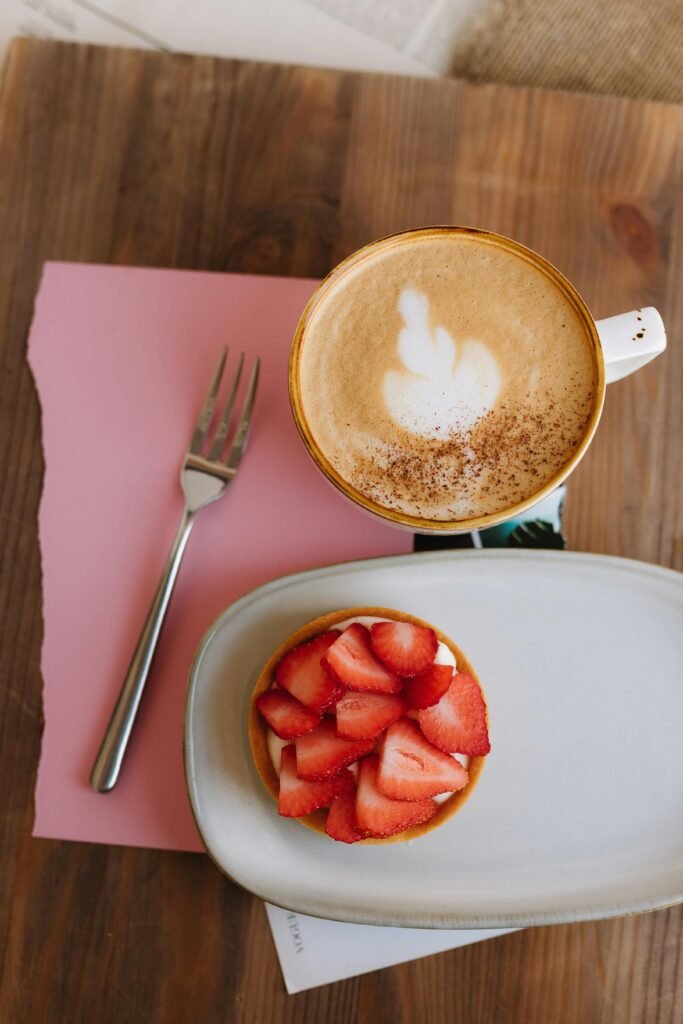 Delicious cappuccino with latte art served with a fresh strawberry tart.