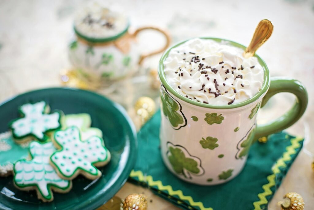 Festive St. Patrick's Day mug with whipped cream and shamrock cookies on a green plate, perfect for themed celebrations.