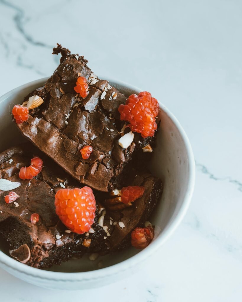 Close-up of chocolate brownies topped with fresh raspberries in a bowl.