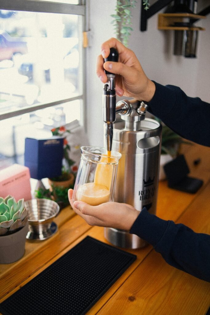 Someone pouring nitro cold brew coffee from a keg dispenser