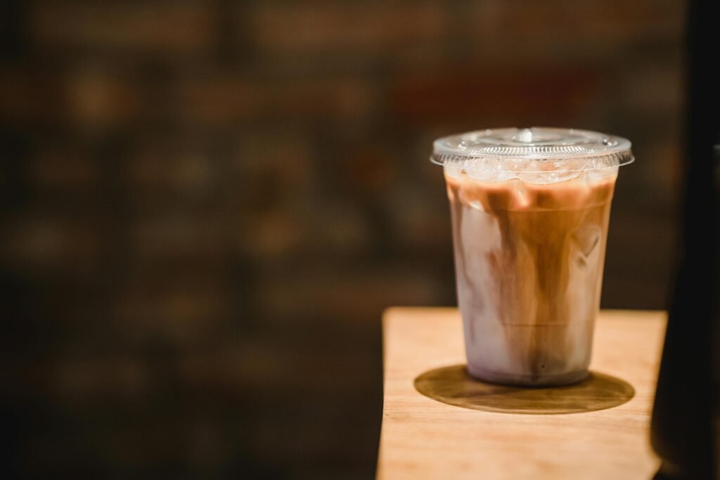 A refreshing iced coffee in a plastic cup on a wooden table, perfect for a caffeine boost.