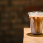 A refreshing iced coffee in a plastic cup on a wooden table, perfect for a caffeine boost.