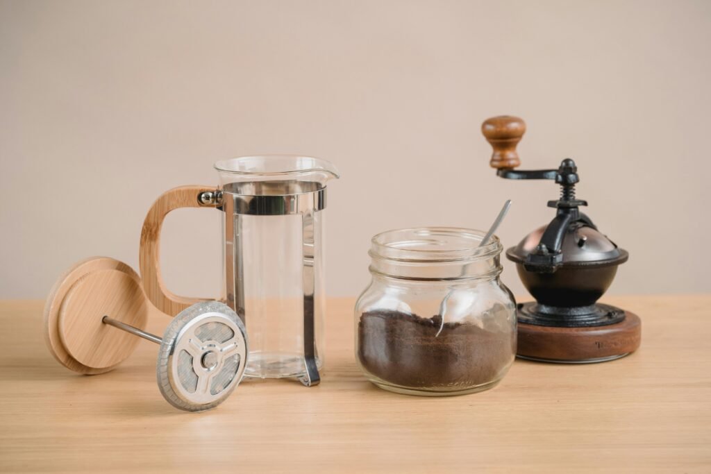 Stylish coffee brewing setup with a French press and vintage coffee grinder on a wooden table.