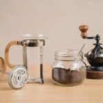 Stylish coffee brewing setup with a French press and vintage coffee grinder on a wooden table.