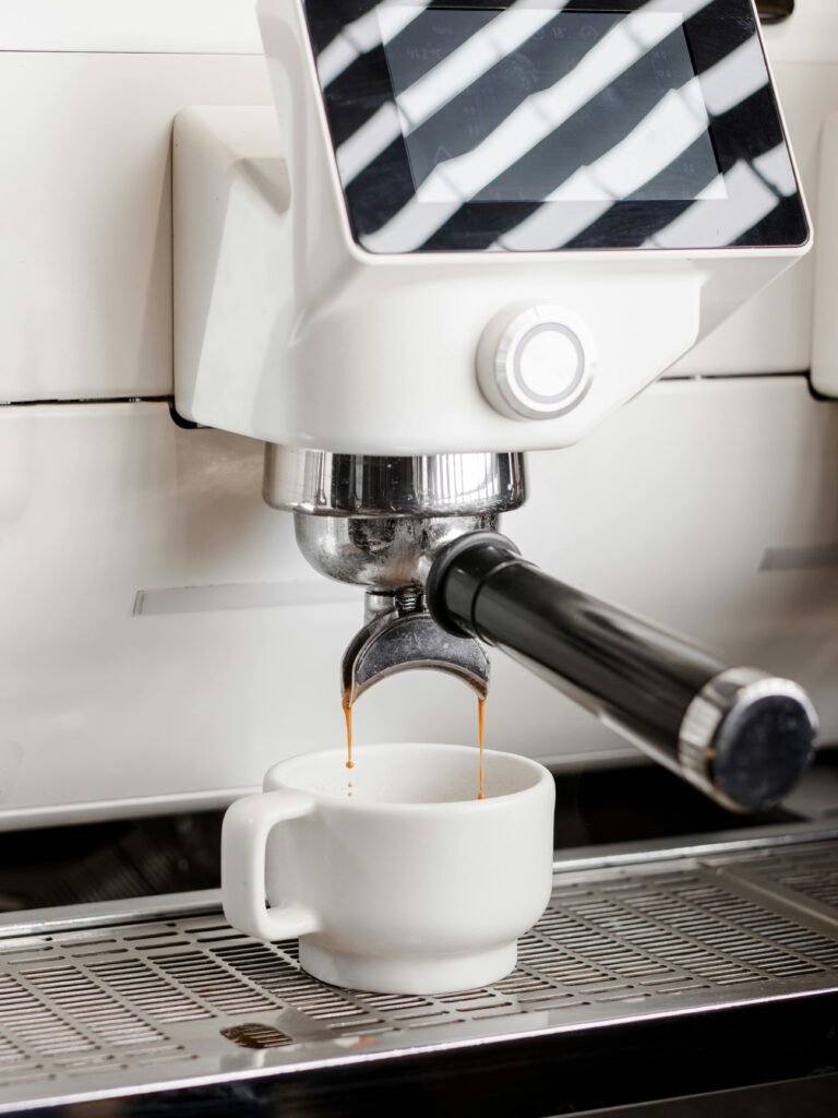 Close-up of espresso machine brewing fresh coffee into a white porcelain cup in a café.