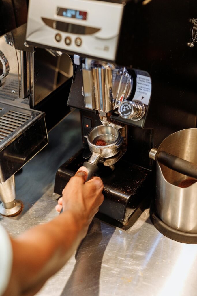 Close-up of a barista using a coffee grinder with a portafilter. Warm and inviting cafe setting.