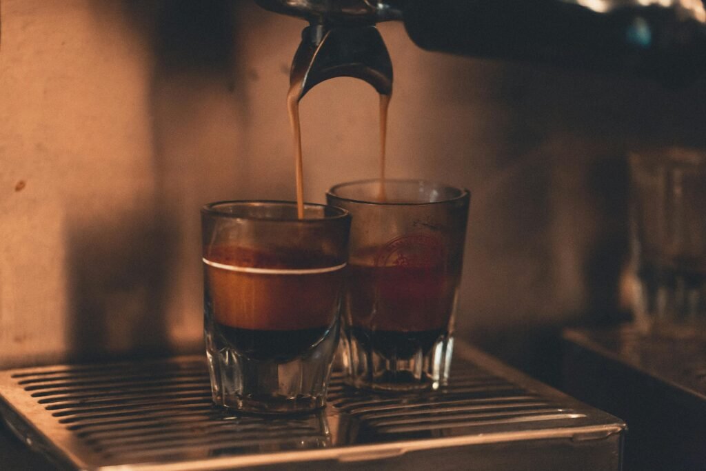 Close-up of hot espresso shots being brewed in a cozy café setting, showcasing rich coffee textures.