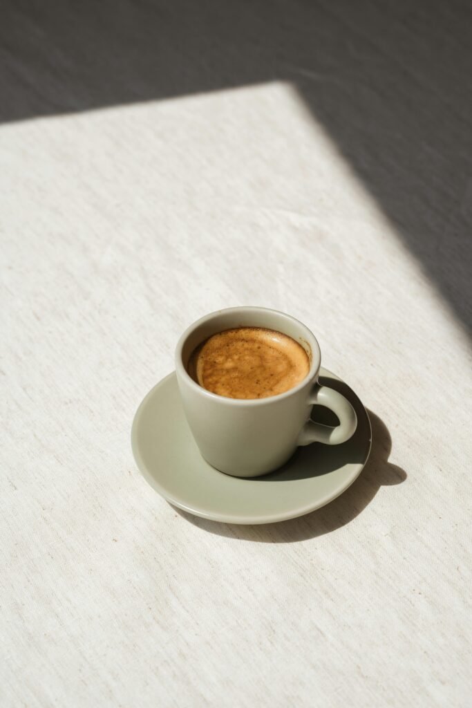A stylish coffee cup filled with espresso on a sunlit table, perfect for cafe-themed designs.