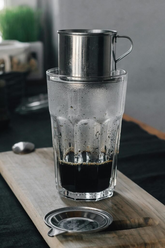Glass of Vietnamese coffee brewed with a stainless steel phin filter.