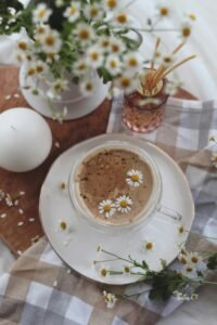 Aesthetic top-down view of a chamomile infused coffee surrounded by flowers and decor.