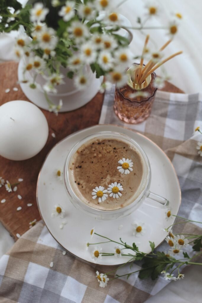 Aesthetic top-down view of a chamomile infused coffee surrounded by flowers and decor.