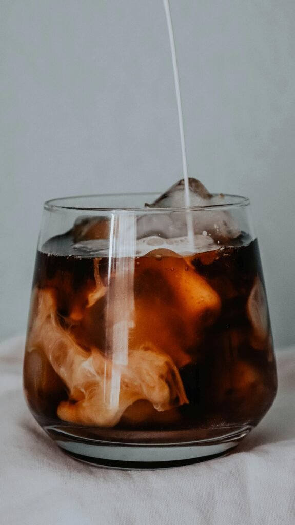 Close-up of refreshing iced coffee in a glass with a swirl of milk, creating a perfect cool beverage.