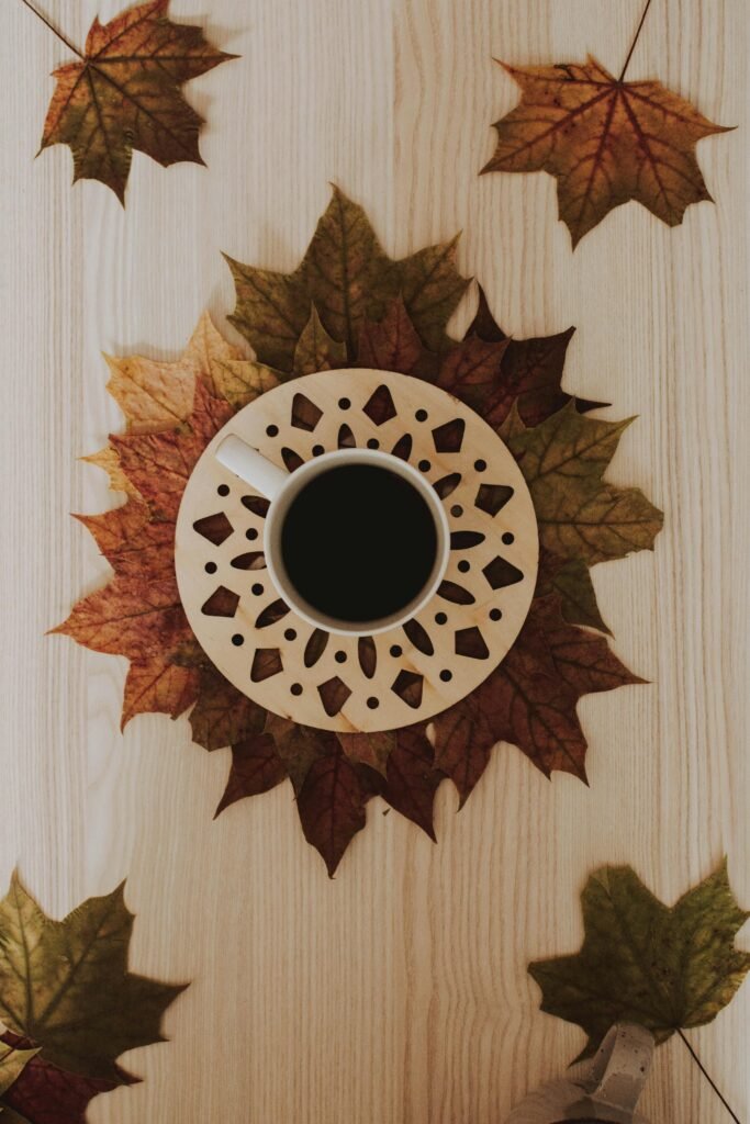 A cozy coffee mug sits atop a circle of autumn maple leaves, inviting a warm fall vibe.