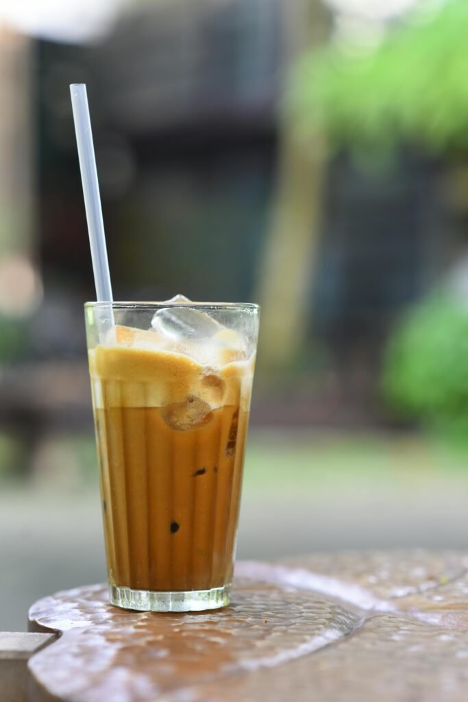A glass of iced coffee with a straw sits on an outdoor table. Perfect for summer refreshment.