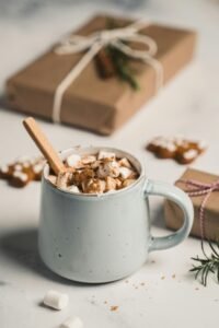A warm mug of hot chocolate with marshmallows surrounded by gifts, capturing the essence of Christmas.